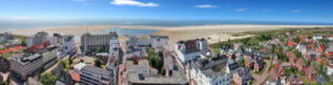 Rooftop-Ansicht eines Küstenstadtviertels mit Strand und Meer im Hintergrund.